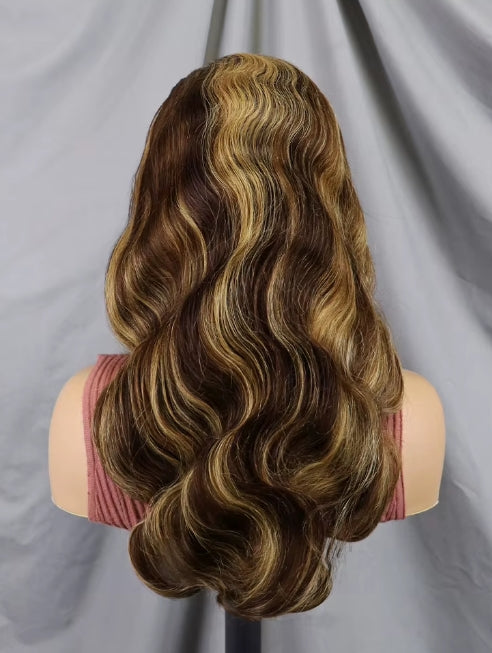 Long wavy wig with highlighted blonde streaks in dark brown, displayed on a mannequin head against a gray fabric backdrop.