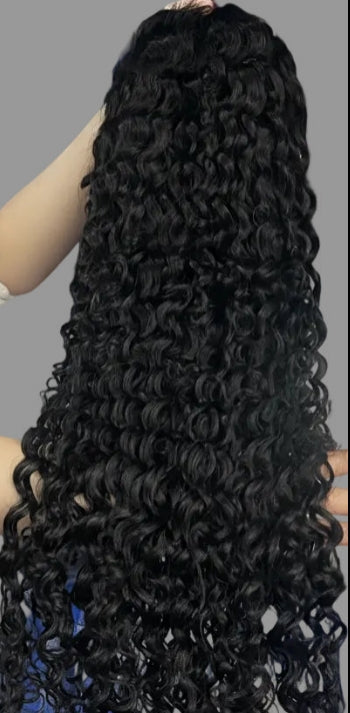 Long, black, deep wave or curly wig with tight spiral curls, shown being held up against a plain gray background.