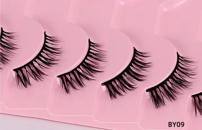Black false eyelashes arranged in a row on a pink plastic tray, with the code BY09 printed in the bottom right corner.