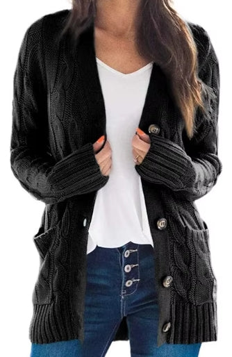 A woman wearing a black cable-knit open-front cardigan with silver buttons, layered over a white top and blue jeans, shown against a plain white background.