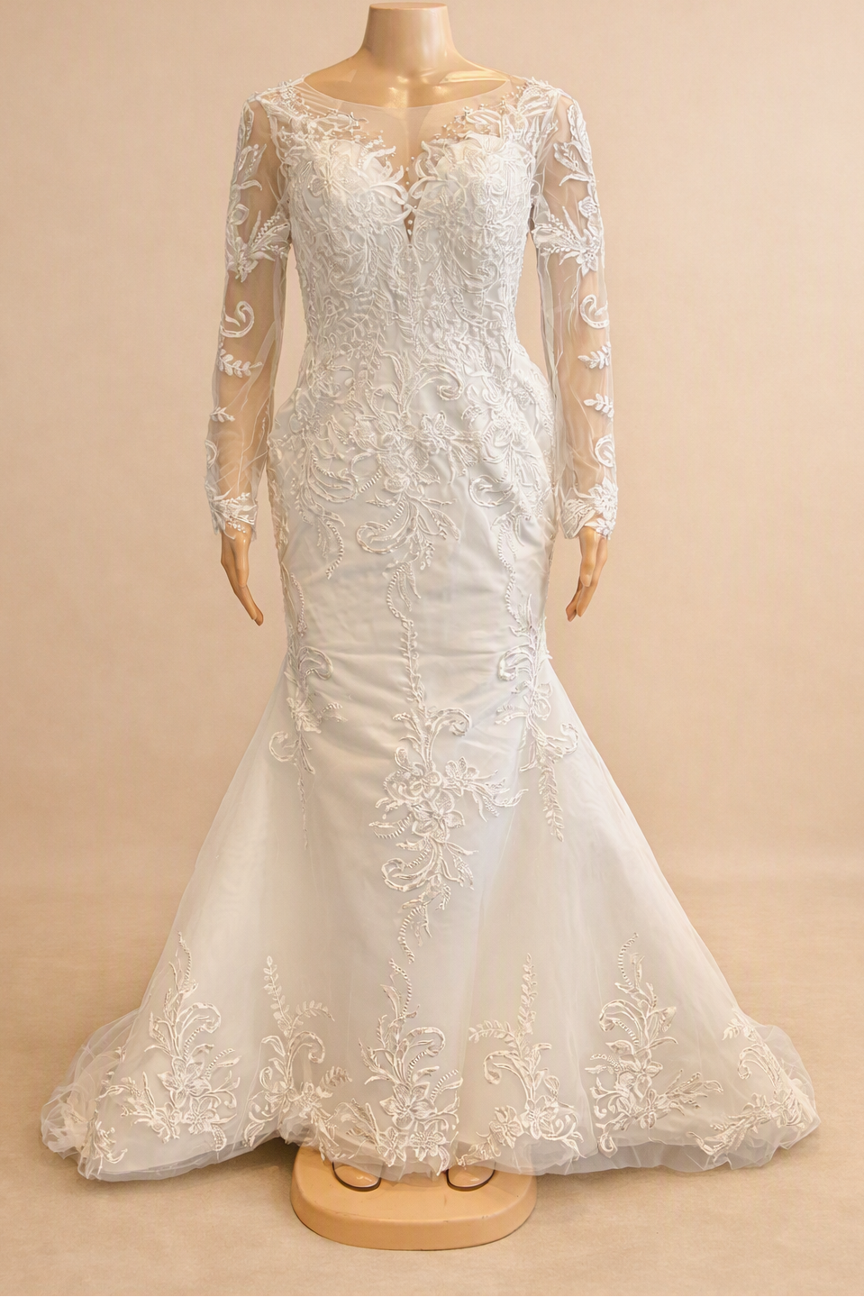 White lace mermaid wedding dress with sheer V-neckline and long floral lace sleeves, front view on mannequin

