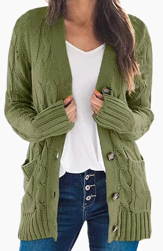 An olive green cable-knit open-front cardigan with button closures and front pockets, worn by a model over a white top and blue jeans.