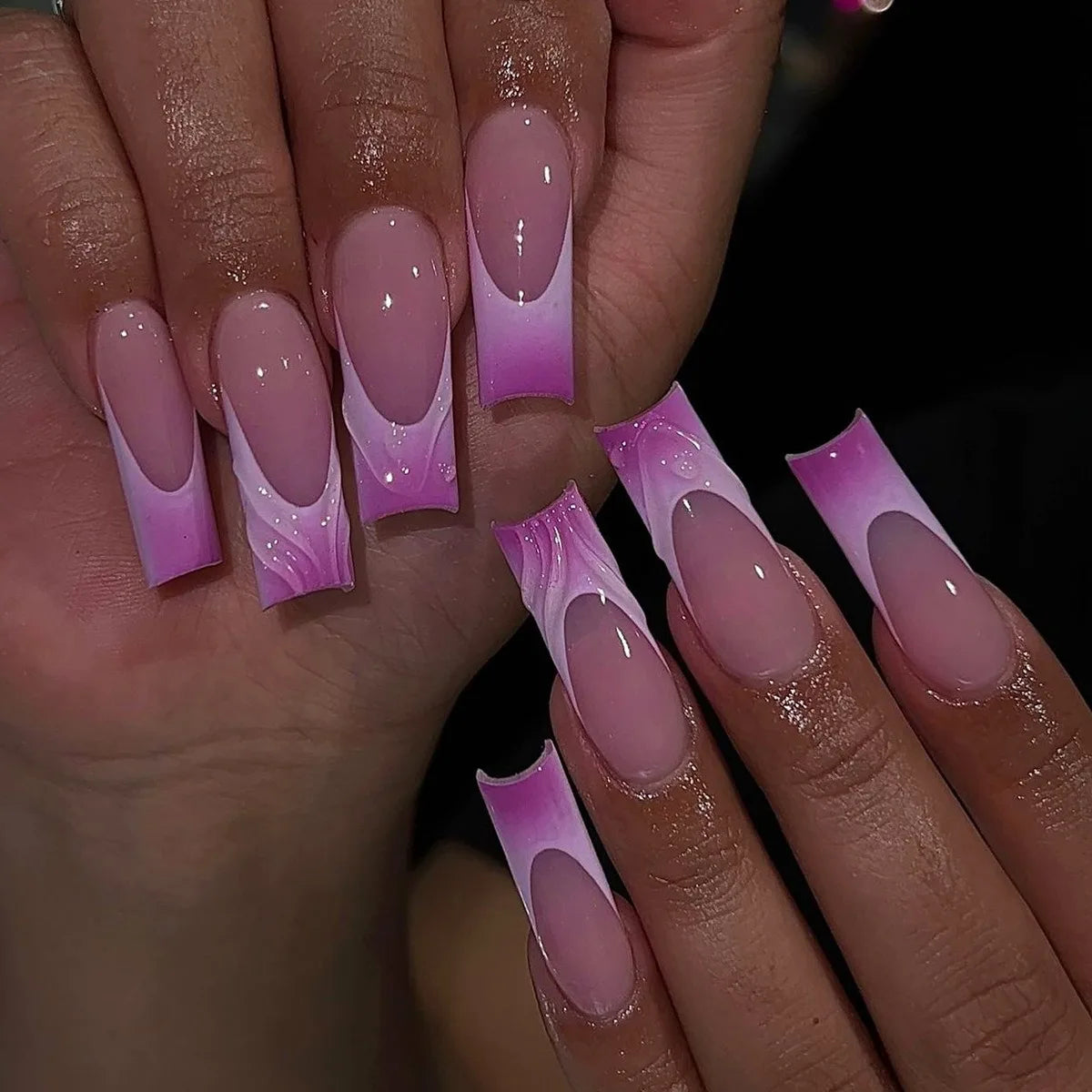 Close-up of hands with pink and purple gradient nail art on a blurred background