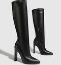Black knee-high boots with a high heel on a light gray background