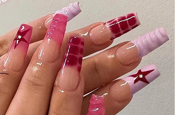 A hand displaying long coffin-shaped press-on nails in a pink gradient set, with a smaller inset showing the individual nail designs. The nails feature various patterns including stripes, stars, and textured tips in shades of pink, red, and white.