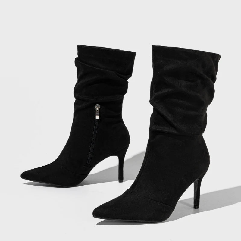 Black high-heeled slouch boots on a light gray background