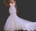 White halter neck lace mermaid wedding dress with beaded sweetheart bodice and cathedral train, front view on dark background


