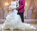 Bride wearing a white ruffled mermaid wedding dress with long lace illusion sleeves and cascading organza ruffle skirt

