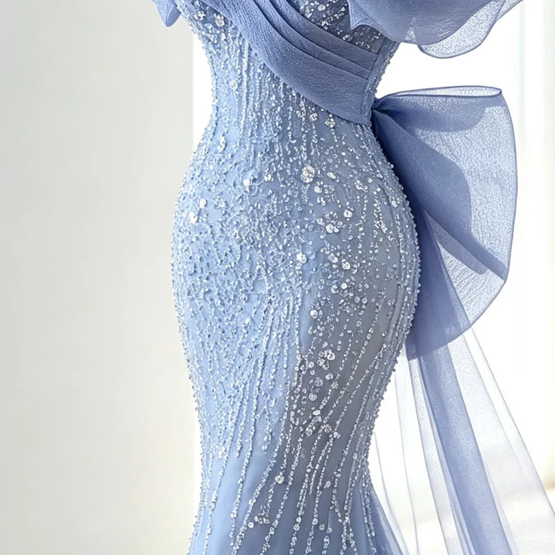 Close-up of all-over sequin and bead embellishment on light blue mermaid gown with oversized bow detail

