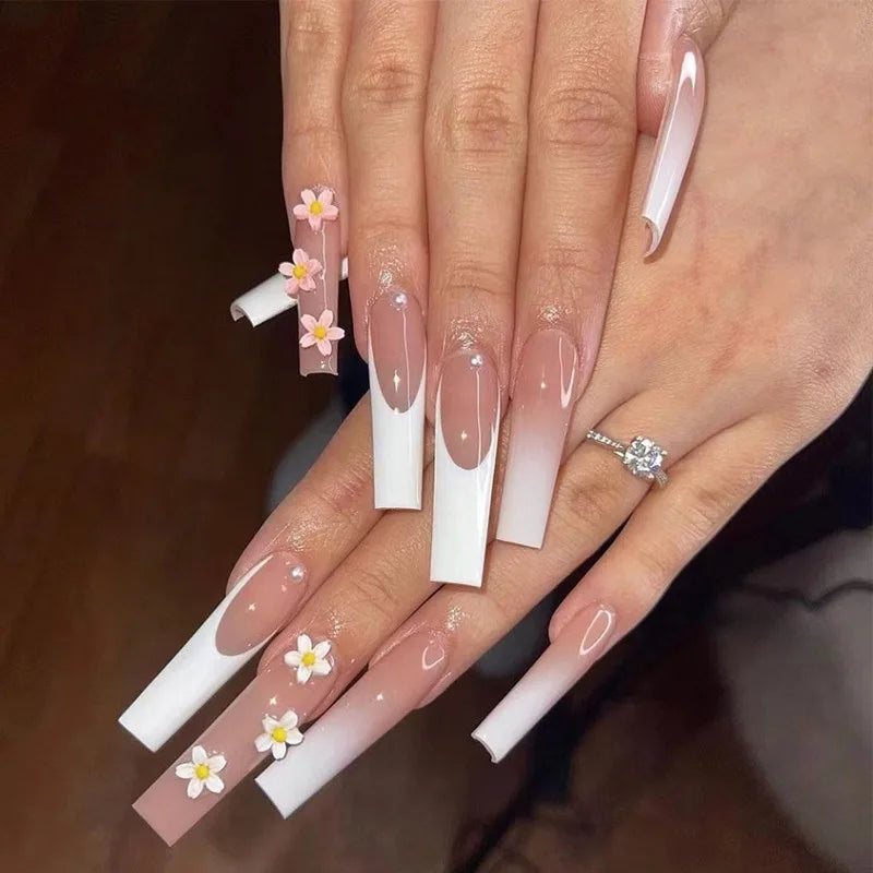 Close-up of a hand with long, decorative nails featuring floral designs.