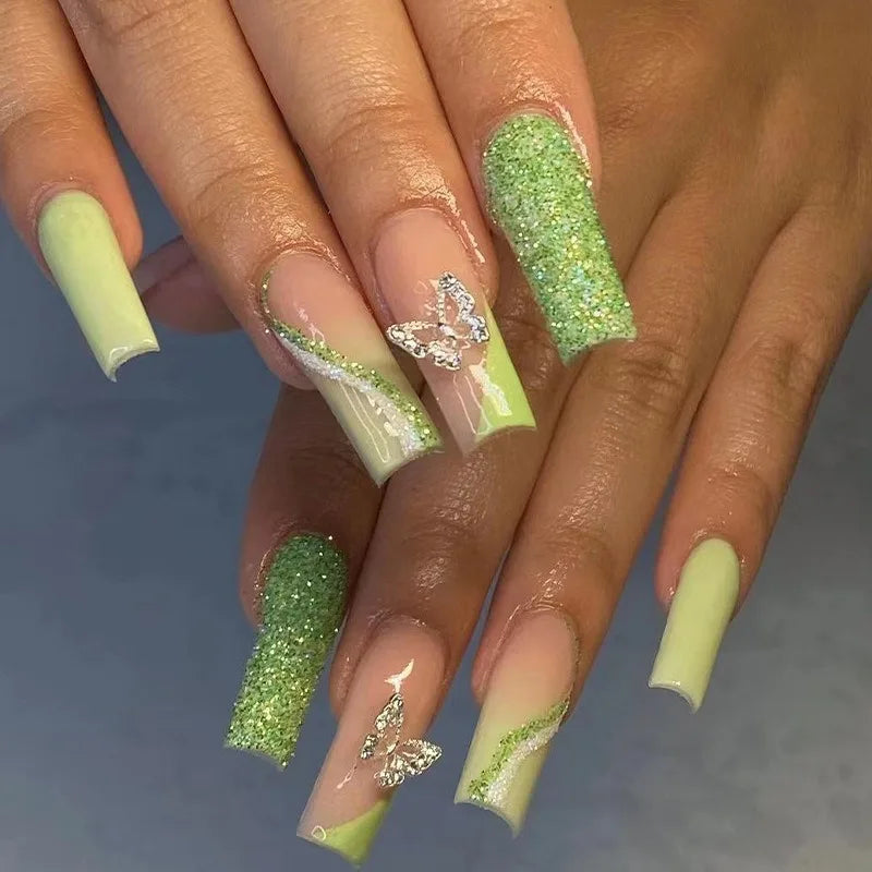 Nails with green glitter and white accents on a neutral background