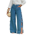 Women's blue wide-leg jeans with 3D denim rose appliqués and side split, front view styled with white blouse and gold heels

