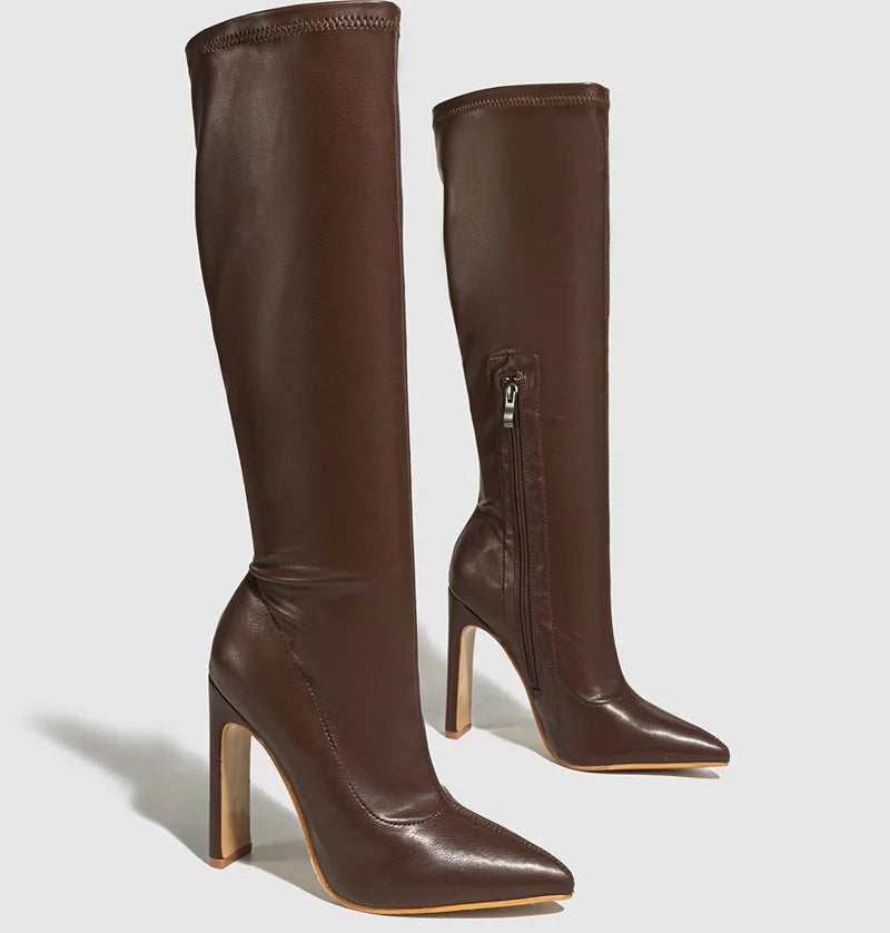 Pair of brown knee-high boots with high heels on a light gray background