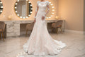 White lace A-line bridal gown with long sheer sleeves and floral appliqués, front view in bridal suite