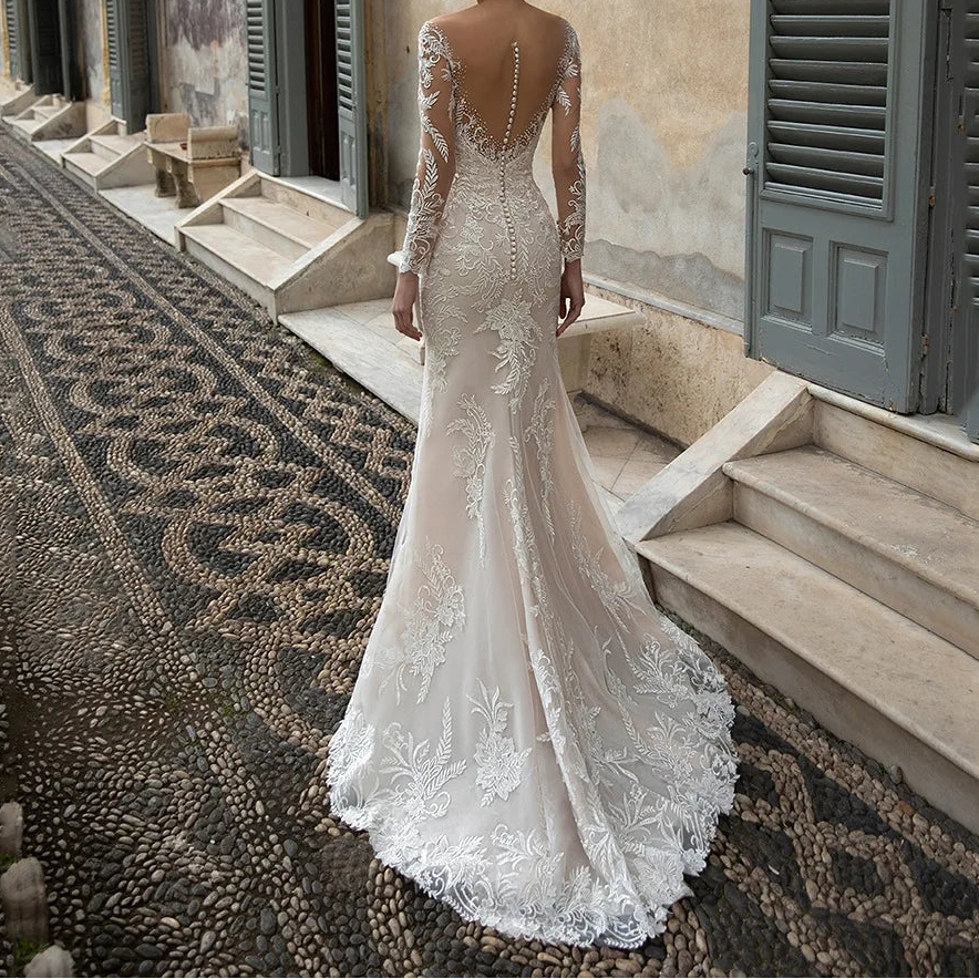  White lace mermaid bridal gown with sheer open back, button detail, and long lace sleeves, back view outdoors

