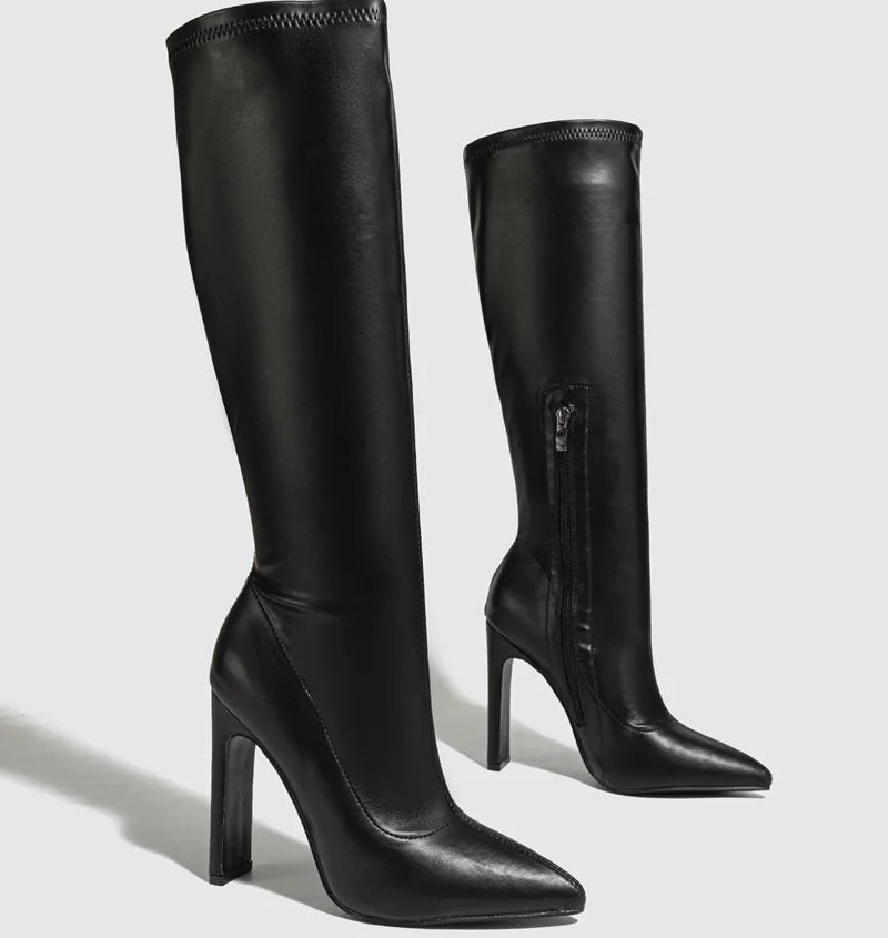 Black knee-high boots with a high heel on a light gray background