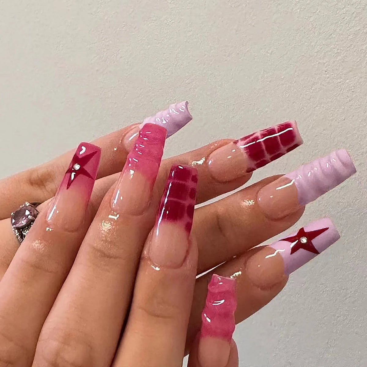 Hand with pink and purple nail art on a plain background