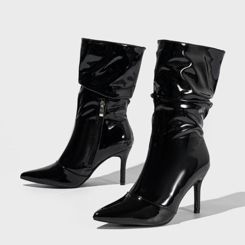 Black patent leather knee-high boots on a light gray background