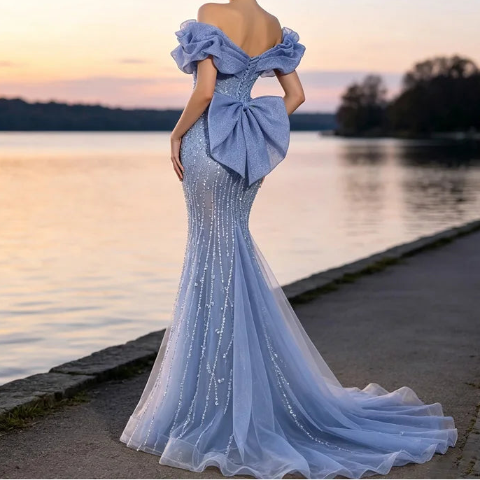 Light blue off-shoulder beaded mermaid gown with oversized bow and cathedral train, back view at lakeside sunset

