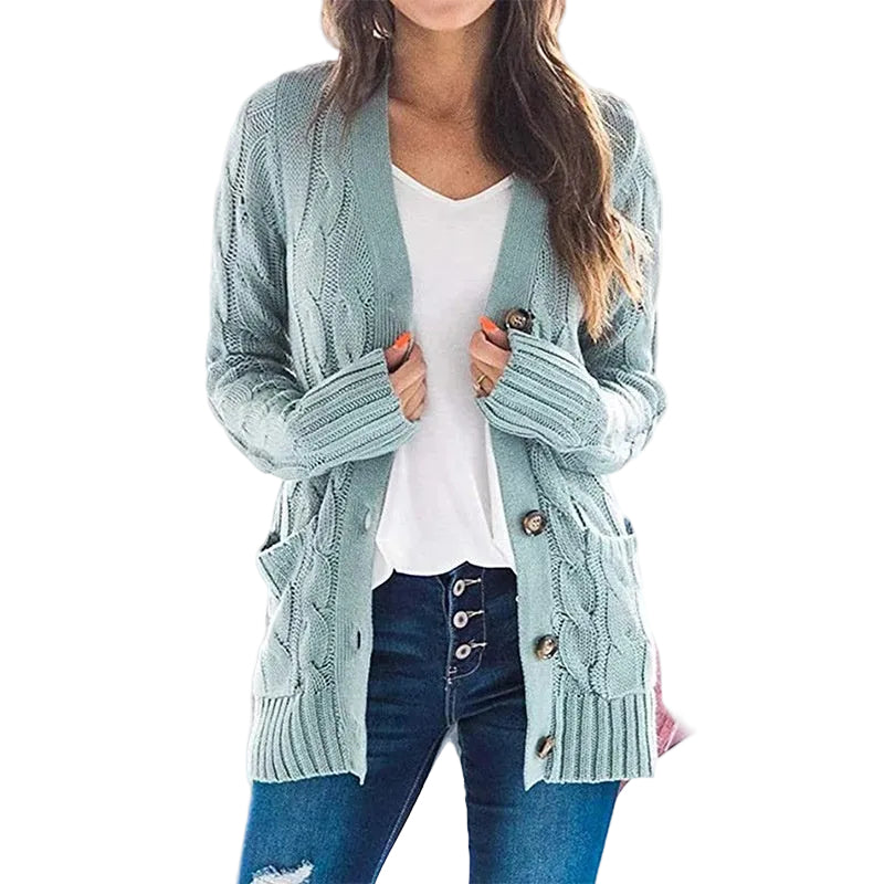A woman wearing a light blue-green cable-knit cardigan over a white V-neck top and blue jeans, shown from the neck down against a plain white background.