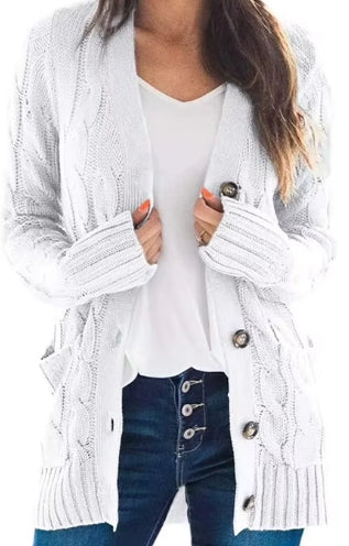 A woman wearing a white cable-knit open-front cardigan with large buttons, layered over a white top and dark blue jeans.
