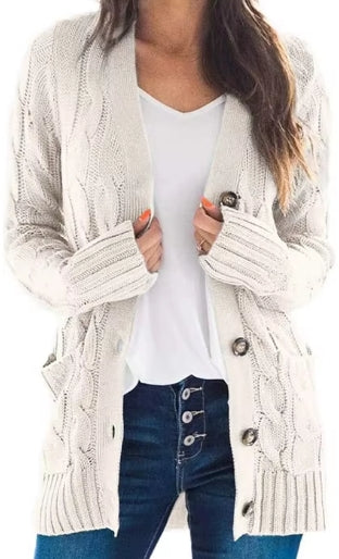 A woman wearing a cream cable-knit cardigan over a white top and blue jeans, shown from the shoulders to the upper thighs against a plain white background.