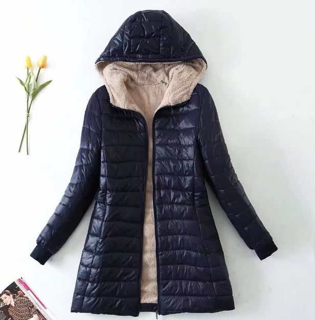 A dark navy hooded puffer jacket with a beige sherpa lining, displayed flat against a white background with a small yellow tulip and a book prop.