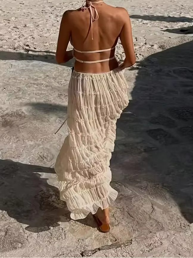 Woman wearing beige halter top and maxi skirt set on the beach.