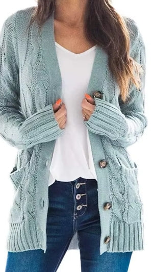A woman wearing a light blue-green cable-knit cardigan over a white V-neck top and dark blue jeans, shown from the shoulders to the upper thighs against a plain white background.