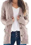 A woman wearing a chunky cable-knit cardigan in a dusty taupe color over a white V-neck top and dark blue jeans.