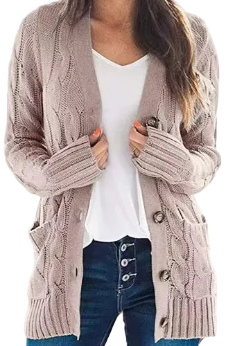 A woman wearing a chunky cable-knit cardigan in a dusty taupe color over a white V-neck top and dark blue jeans.