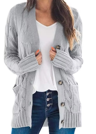 A woman wearing a light gray cable-knit cardigan over a white top and blue jeans, shown from the shoulders to the upper thighs against a plain white background.